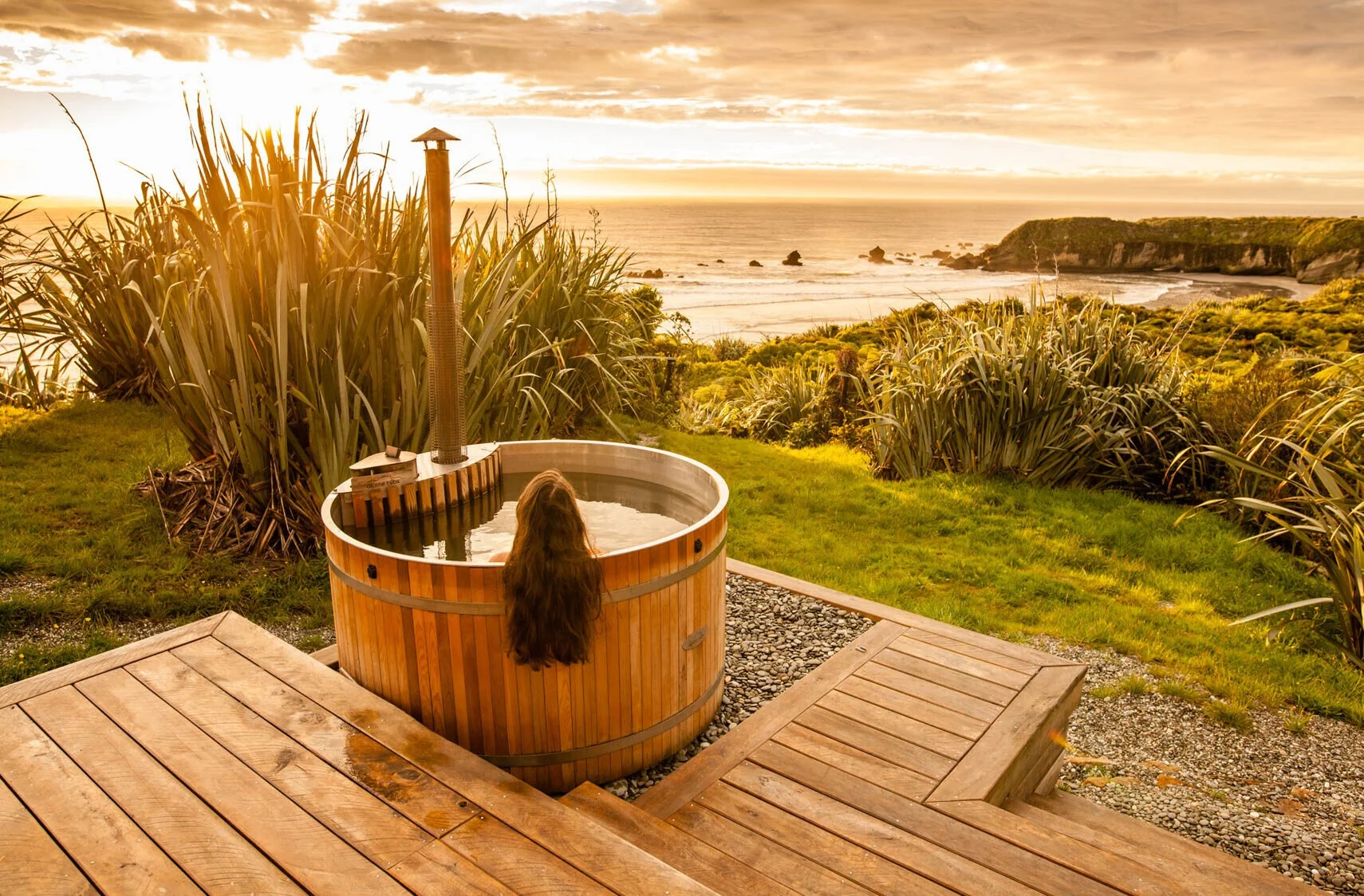 Round wood-fired hot tub installed on a coastal deck