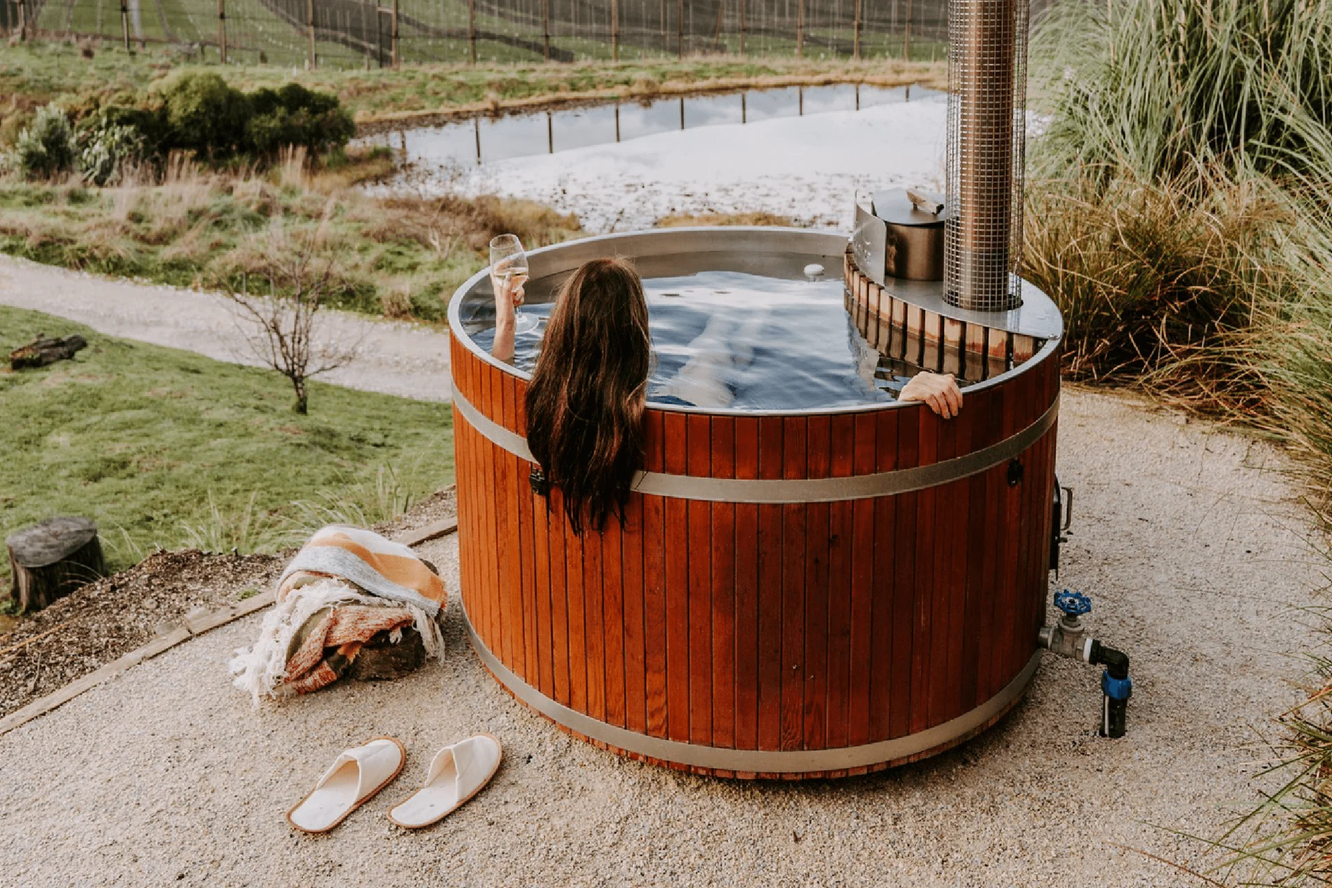 Round wood-fired hot tub installed on a rural deck