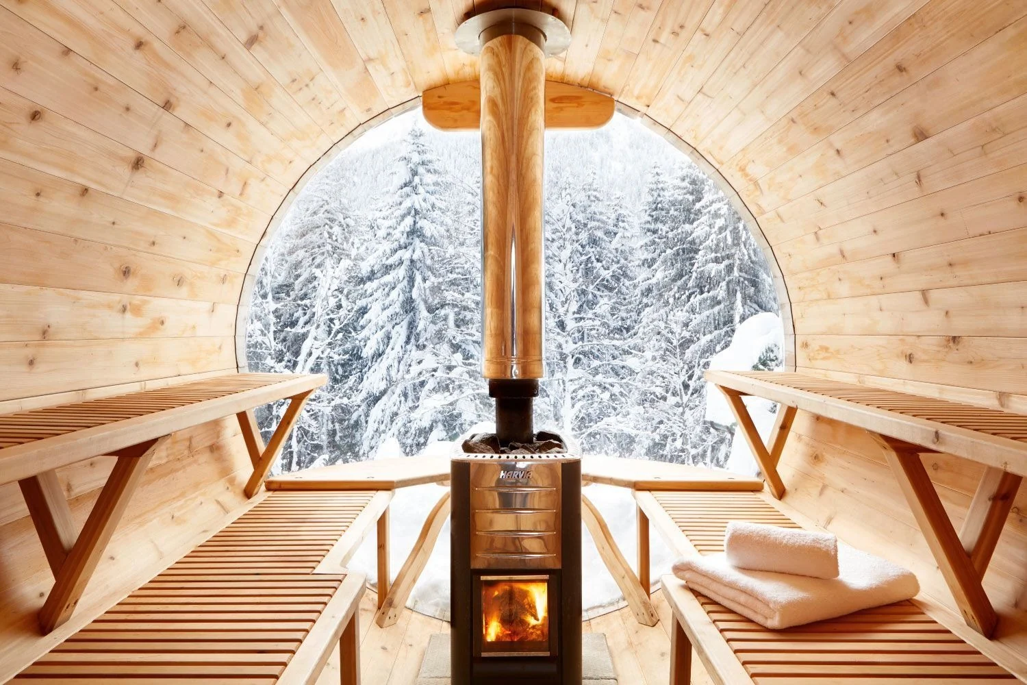 Traditional indoor sauna with a wood stove and panoramic window