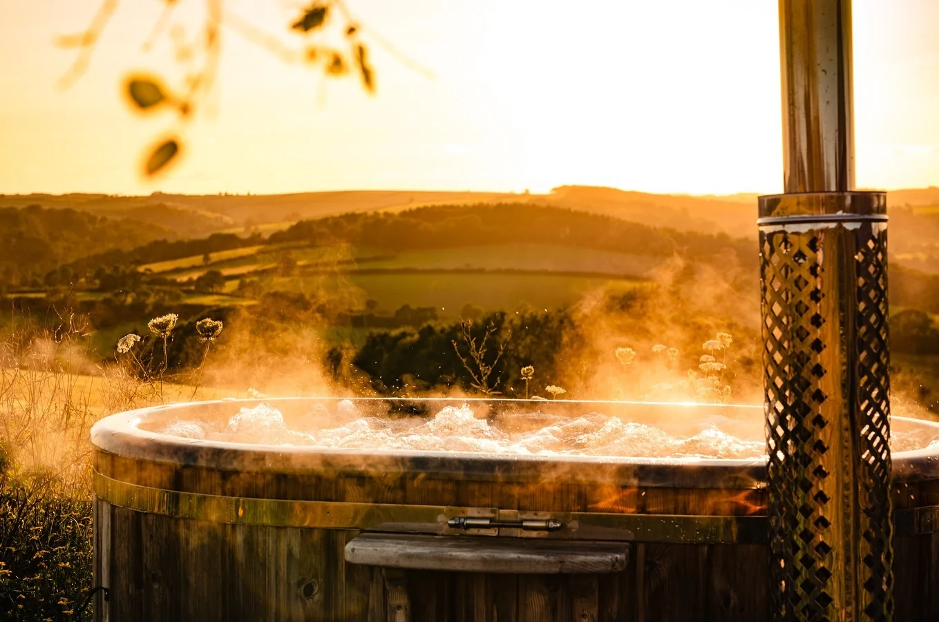 Wood-fired hot tub with external chimney in a landscape