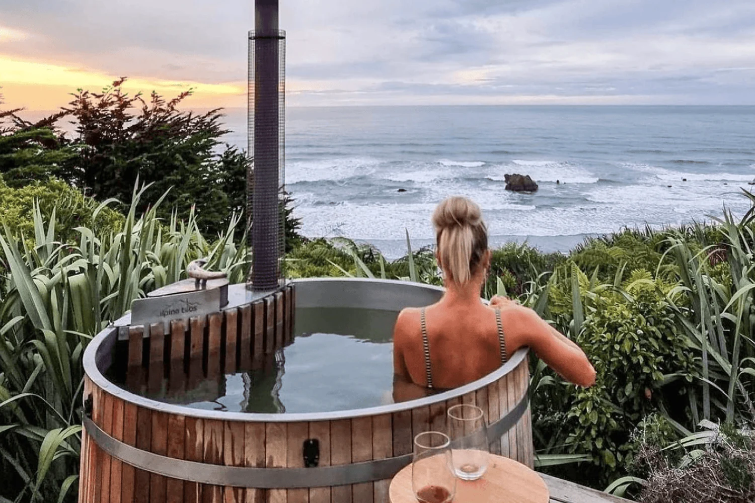 Persona usando una bañera nórdica calentada con leña junto al mar