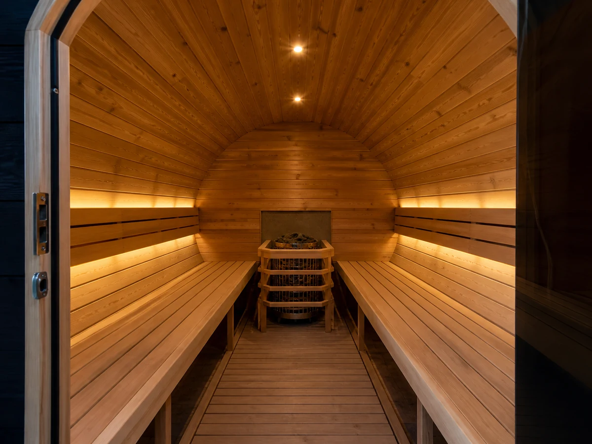 Wide angle barrel sauna interior showing curved shell benches heater guard doorway and usable aisle