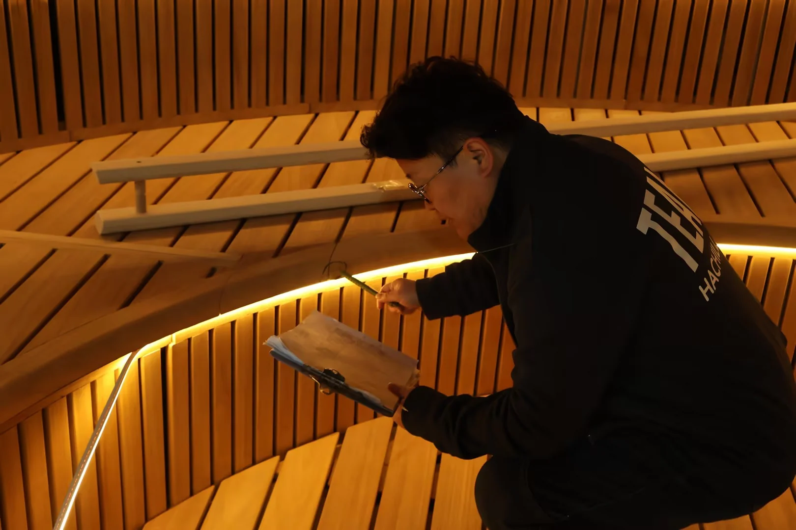Factory worker fitting a timber bench inside a sauna
